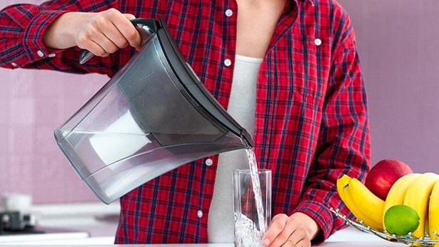 ragazza che versa acqua da una caraffa filtrante